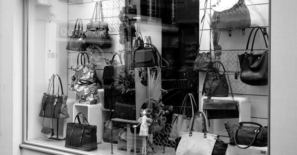 Black and white photo of a boutique window showcasing luxury handbags on display.